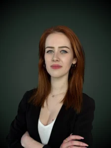 Magdalena Witos specjalista ds. kredytów walutowych w czarnym garniturze i założonymi rękoma na zielonym tle