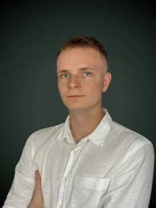 Przemek Maciejczyk specjalista kredytów walutowych w białej koszuli na szarym tle