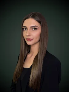 Emilia Durbas asystent prawny w czarnej marynarce z długimi włosami na ciemnym tle