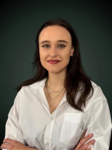 Joanna Gał specjalista procesu sądowego w białej marynarce z założonymi rękoma na ciemnym tle