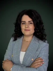 Joanna Pusz specjalista procesu sądowego w niebieskiej marynarce z założonymi rękoma na ciemnym tle