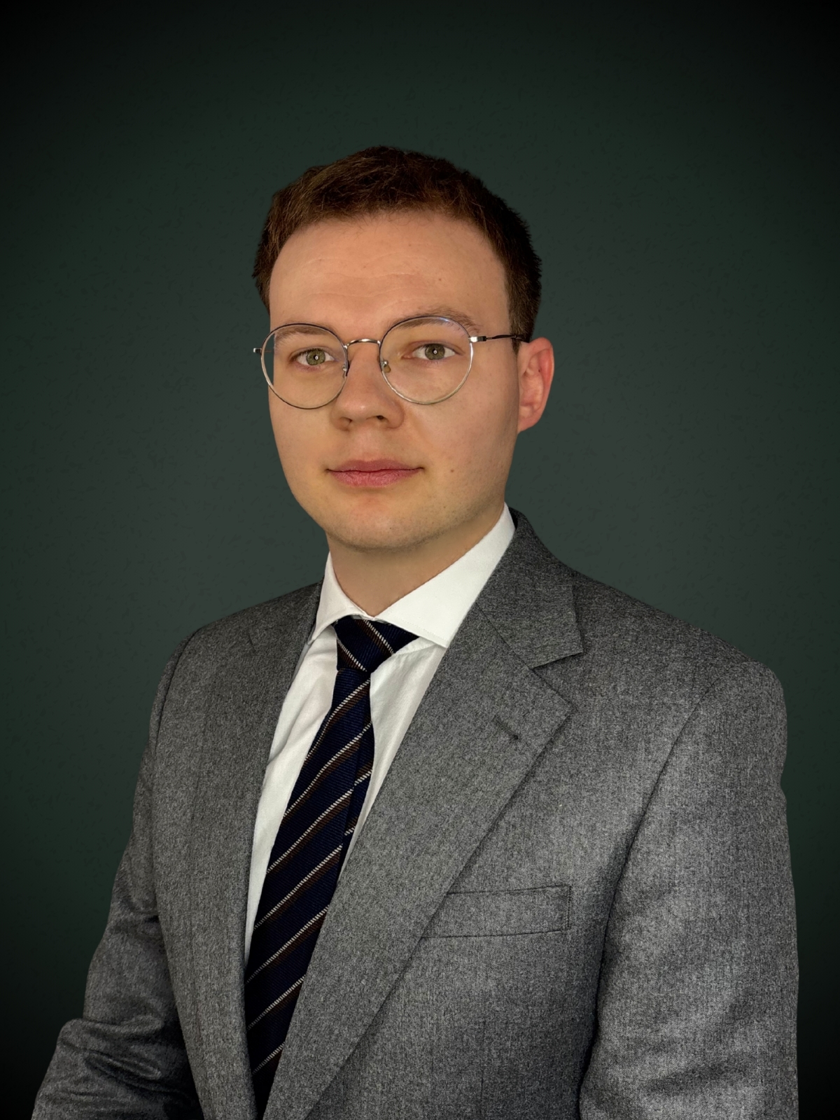 Michał Milasz dyrektor działu prawnego w szarym garniturze i okularach na ciemnym tle