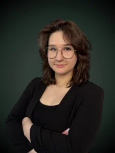 Oliwia Bzdyra starszy konsultant w czarnej marynarce i okularach na szarym tle