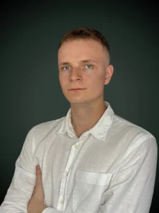 Przemek Maciejczyk specjalista kredytów walutowych w białej koszuli na szarym tle