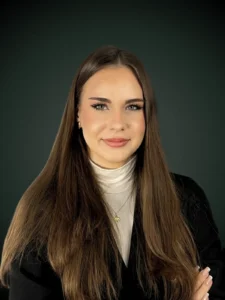 Iga Krusinowska starszy asystent prawny w beżowej marynarce i białej bluzce na ciemnozielonym tle, Franki Kancelaria odzyskujemy kredyty CHF i euro